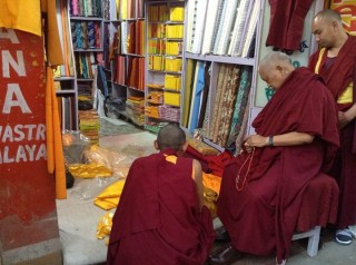 Lama Zopa Rinpoche carefully choosing the cloth that will be offered as robes for the Buddha statue at Mahabodhi Stupa. 