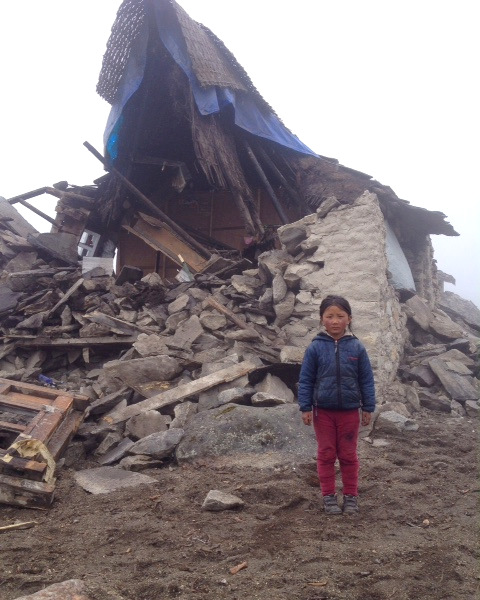 Young girl stands next to a collapsed home in Thame, Solu Khumbu district, Nepal, April 28, 2015. Photo by Jimmy Grant.