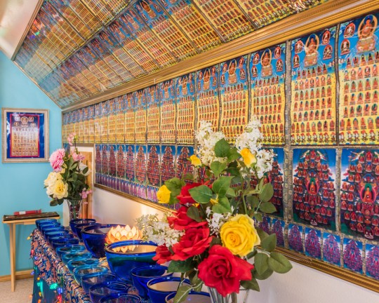 Offering and dozens of images of the 35 buddhas of confession in Lama Zopa Rinpoche's room at Buddha Amitabha Pure Land, Washington, US, June 2015. Photo by Chris Majors.
