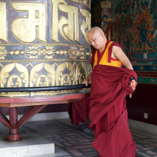 Lama Zopa Rinpoche turning the large prayer wheel at Kopan Monastery, Nepal, November 2015. Photo by Bill Kane.