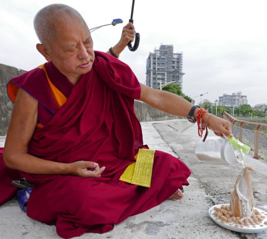 Lama Zopa Rinpoche doing naga torma puja by the river, Taiwan, May 2016. Photo by Ven. Roger Kunsang.
