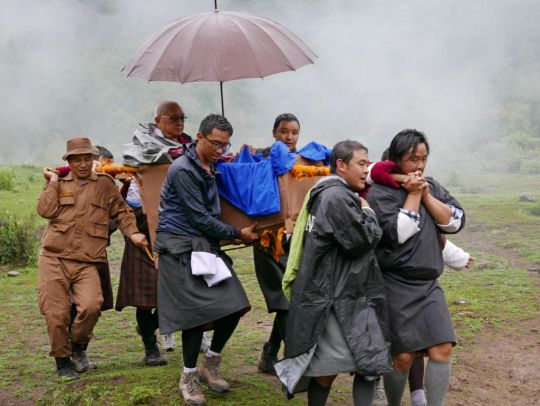 Lama Zopa Rinpoche arrives back at the trailhead after three hours in the rain with the assistance of generous volunteers, Tiger's Nest, Bhutan, May 2016. Photo by Ven. Roger Kunsang.