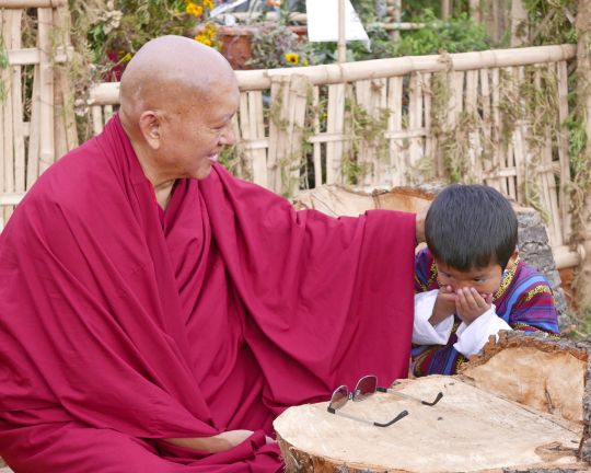 Lama Zopa Rinpoche and a young boy covering his mouth in respect, Paro, Bhutan, June 2016. Photo by Ven. Roger Kunsang.