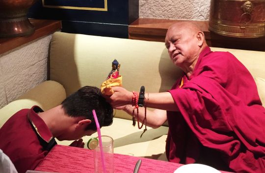 Lama Zopa Rinpoche blesses a waiter in a restaurant in Thailand, June 2016. Photo by Ven. Holly Ansett.