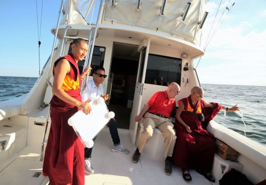 Lama Zopa Rinpoche pours blessed water into the Atlantic Ocean off New York, USA, August 2016. Ven. Sangpo is holding a laminated Namgyalma mantra in his hand in preparation for putting it into the ocean. Photo by Ven. Lobsang Sherab.