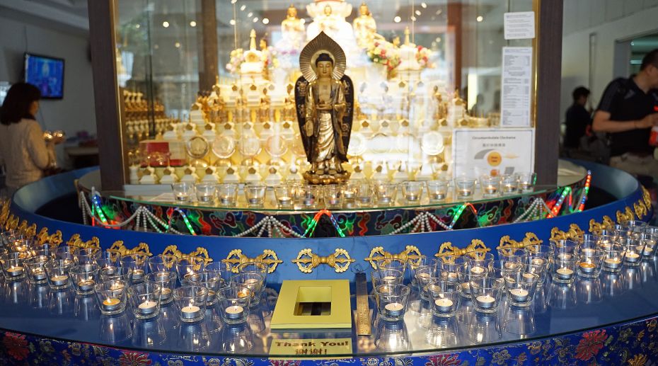 Buddha statue surrounded by candle light offerings at Amitabha Buddhist Centre in Singapore