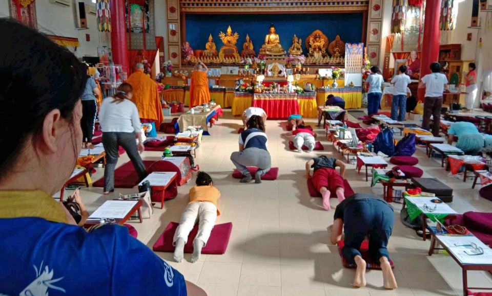 nyung na retreat participants performing prostrations while facing the altar in the large rinchen jangsem ling retreat center gompa.