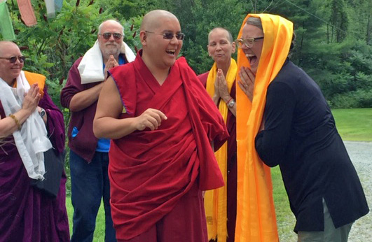 His Eminence Ling Rinpoche and milarepa center director dawn holtz outside smiling and laughing together while a few people look on smiling.