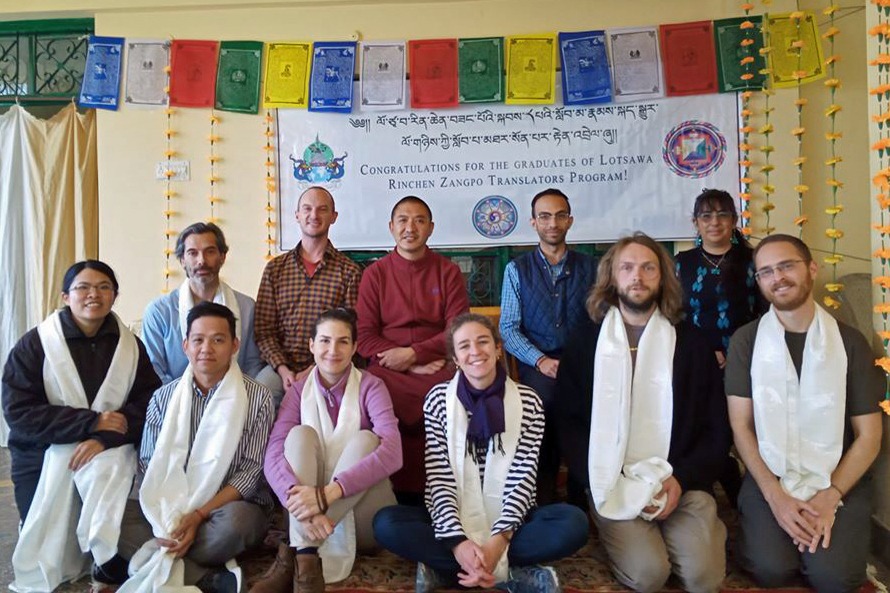 Eleven people posing for a group photo wearing khatas.