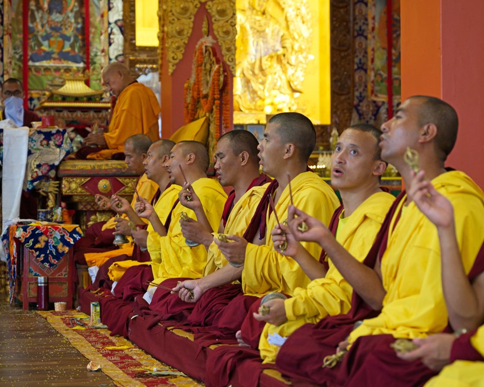 monks holding incense sticks during puja