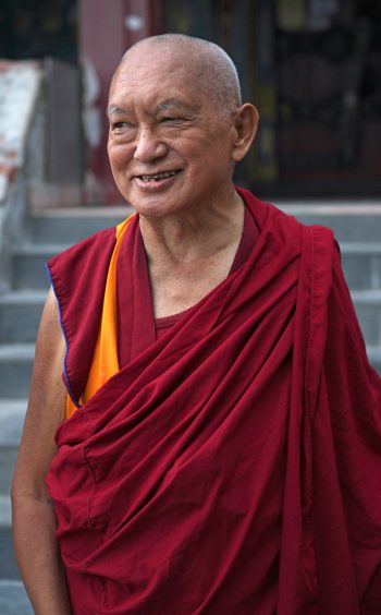 Lama Zopa Rinpoche smiling in front of the Kopan Gompa