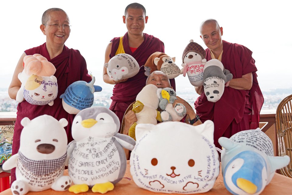Lama Zopa Rinpoche surrounded by stuffed toys with Dharma messages on them