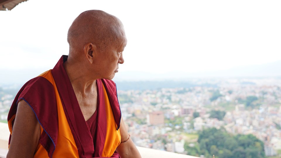 Lama Zopa Rinpoche looking out over buildings and landscape surrounding Kopan Hill