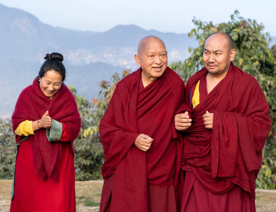 Khadro-la and Lama Zopa Rinpoche with attendant Ven. Thubten Tendar walking outside with a view of hills in the distance