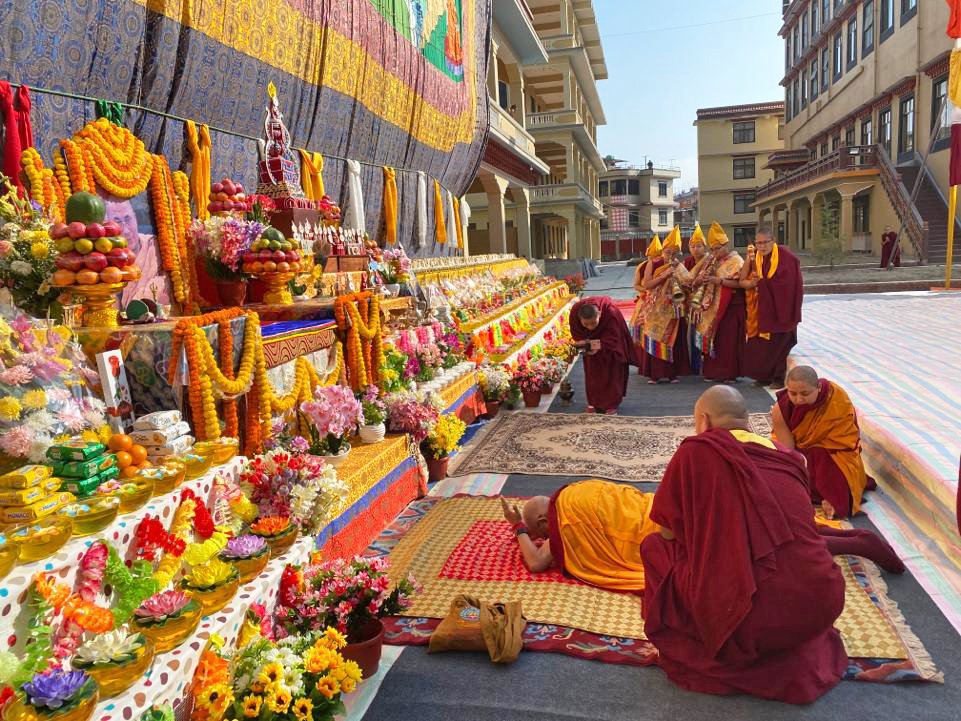 Lama Zopa Rinpoche in full prostration before the Guru bumtsok altar below the giant Guru Rinpoche thangka