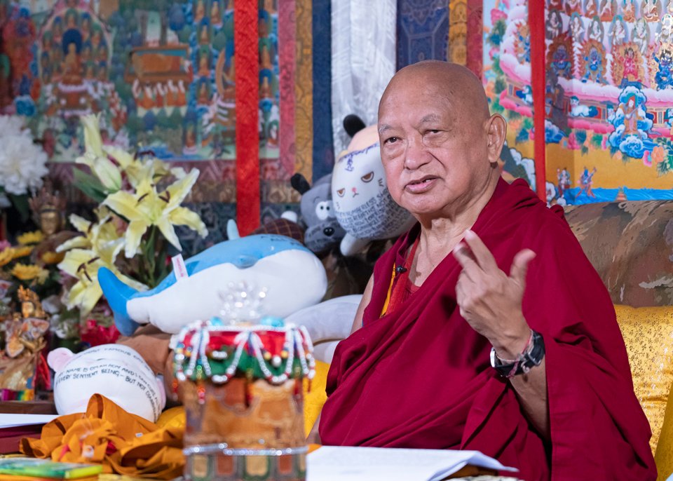 lama zopa rinpoche sitting on a couch teaching and making a gesture with his hand