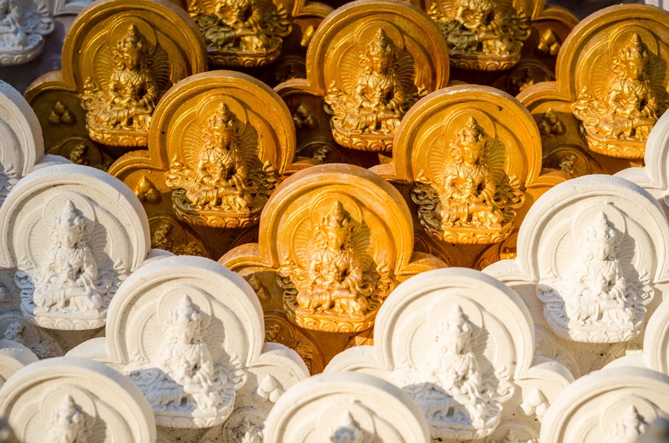 many tsa-tsa statues, some are painted gold, some are white