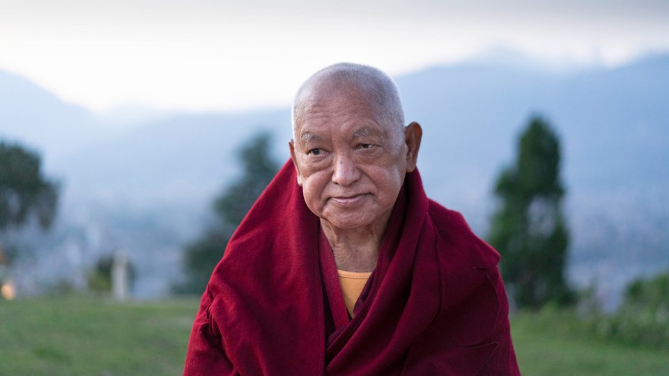 Lama Zop Rinpoche standing outside with foothills in the background