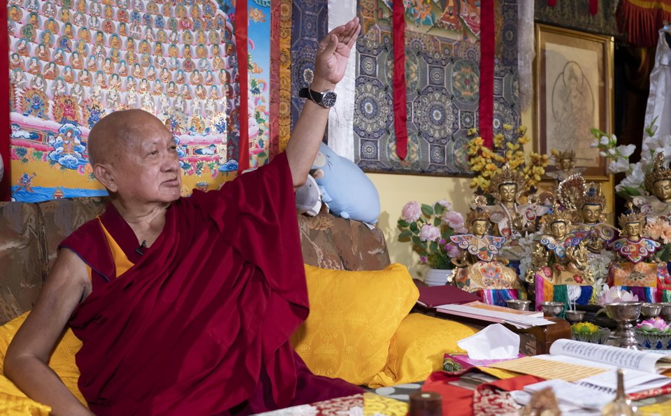 Rinpoche seated on a couch, teaching and gestering with his arm