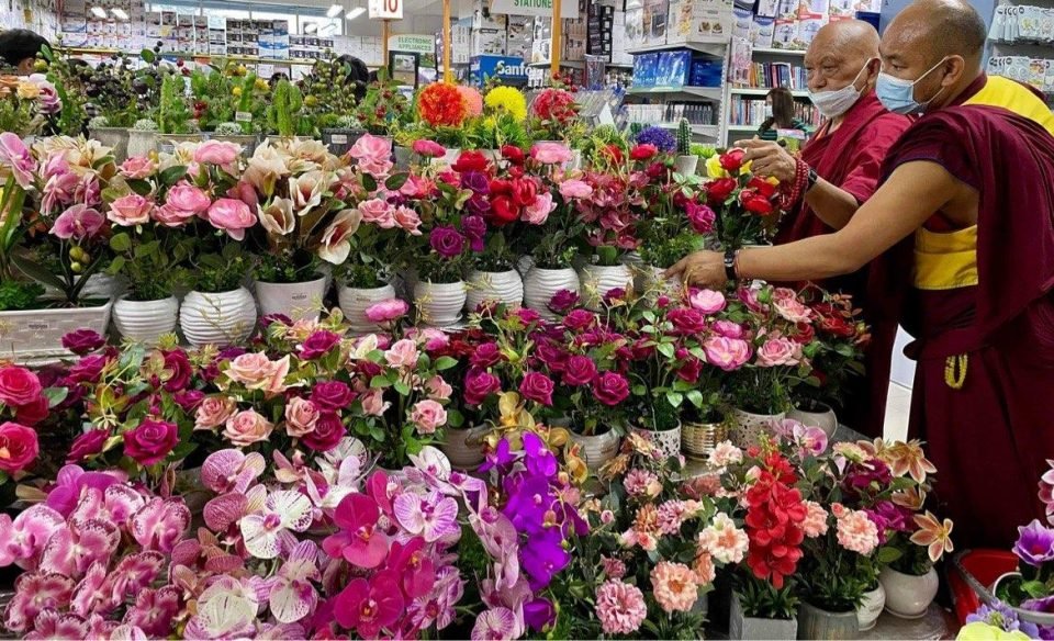 Rinpoche looking at shelves of blooming flowers in a store