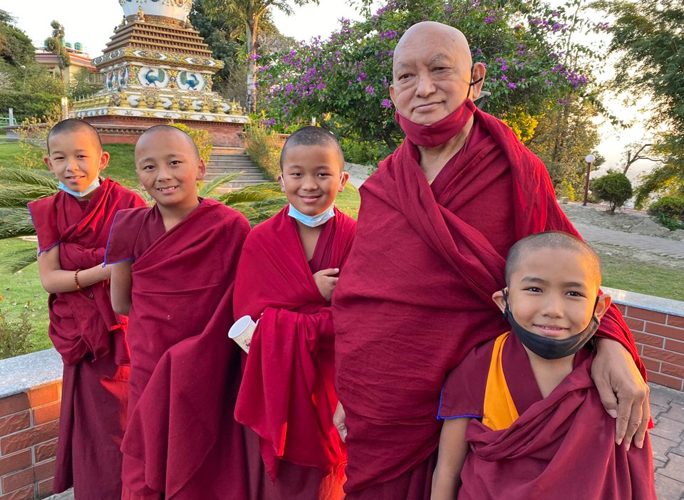 Lama Zopa Rinpoche standing with four young monks in the stupa garden at Kopan Monastery