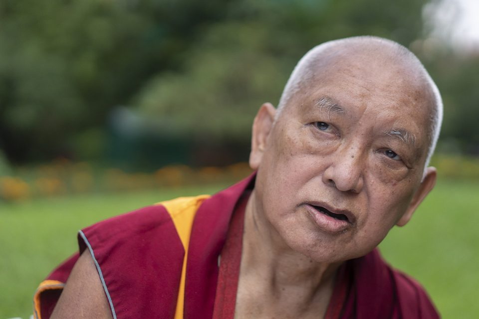 Lama Zopa Rinpoche talking in a green garden