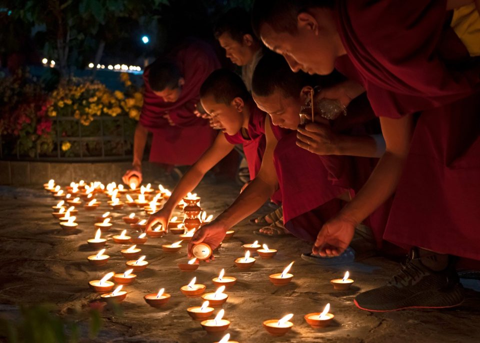 Monks lighting dozens of candles at night