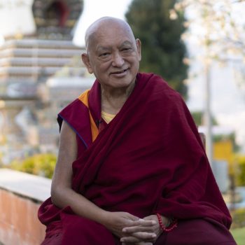Lama Zopa Rinpoche sitting in front of a stupa. 