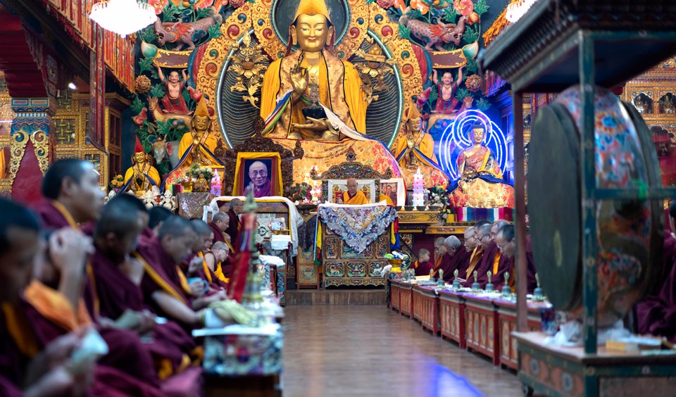Traditional Tibetan monastery altar room with monks doing ceremonial puja