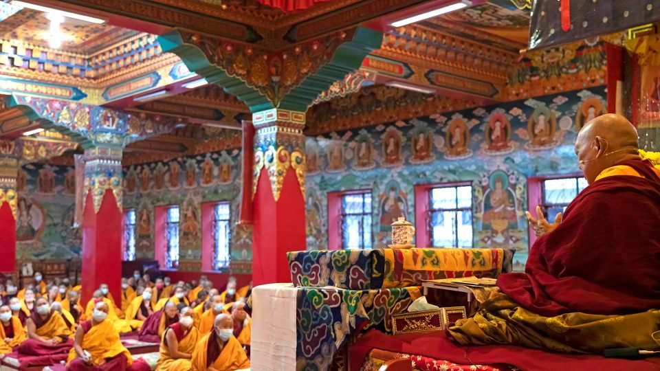 View of Rinpoche teaching in front of nuns in a large gompa
