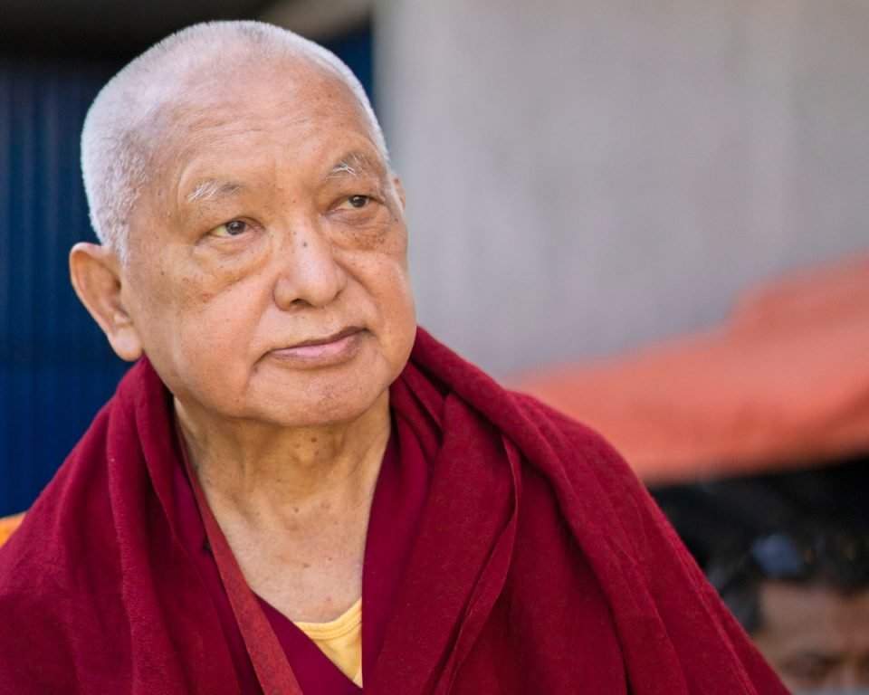 close up of Lama Zopa Rinpoche looking into middle distance