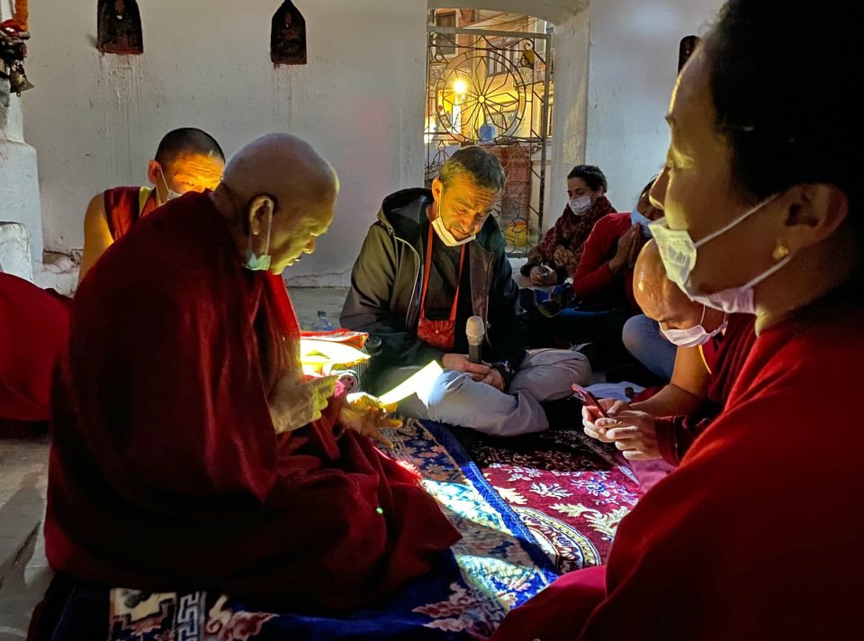 Lama Zopa Rinpoche and students doing practice at night seated on a rug