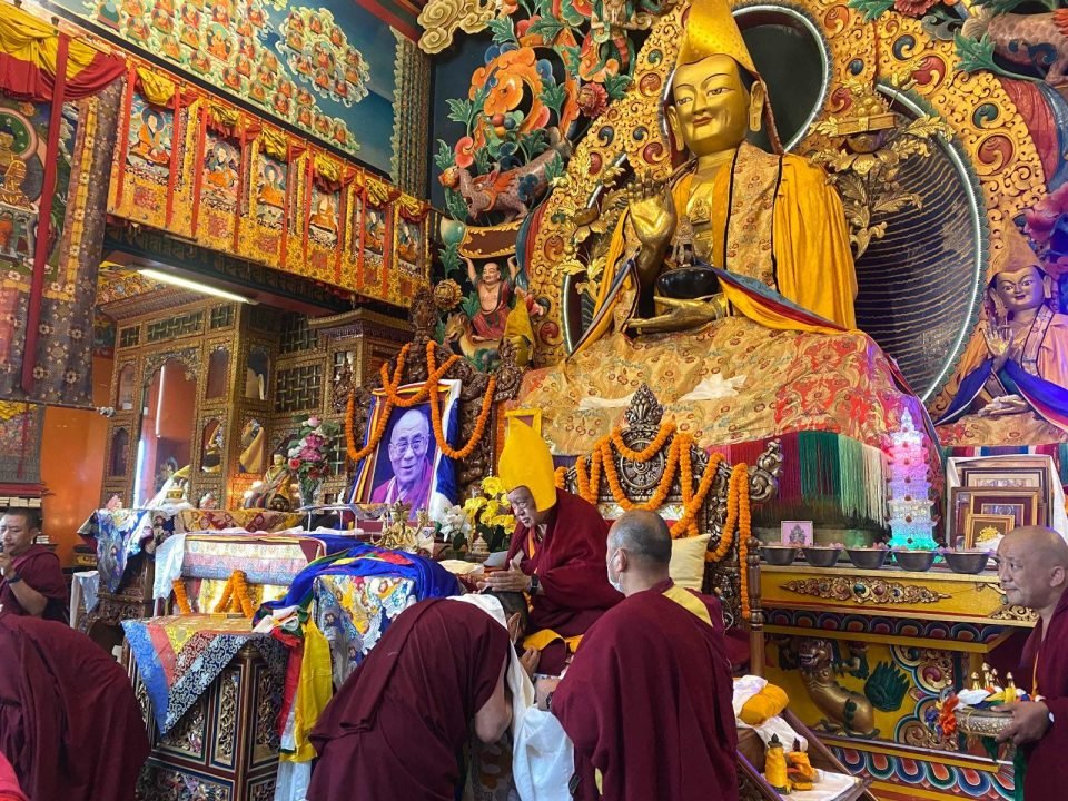 Lama Zopa Rinpoche seated on throne in front of large Lama Tsongkhapa statue
