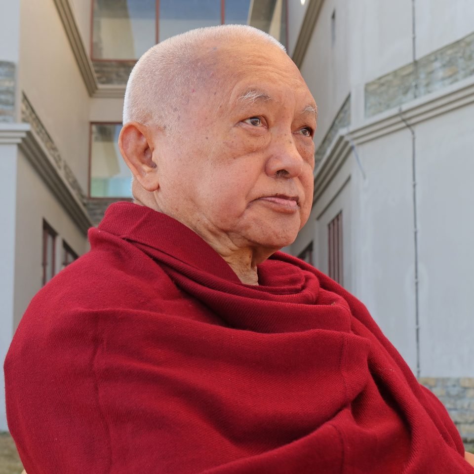 Lama Zopa Rinpoche sitting and looking thought