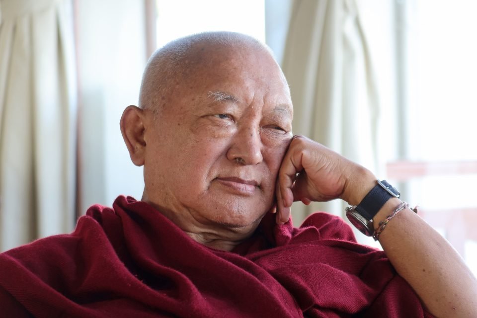 Lama Zopa Rinpoche sitting and looking thought