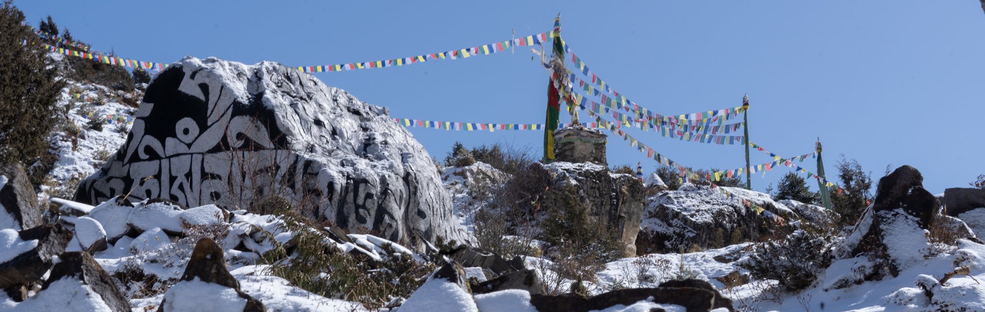 prayer flags and mani stones in the snow under a blue sky