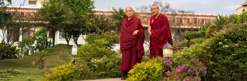 Lama Zopa Rinpoche and Khen Rinpoche Geshe Chonyi walking in a garden.