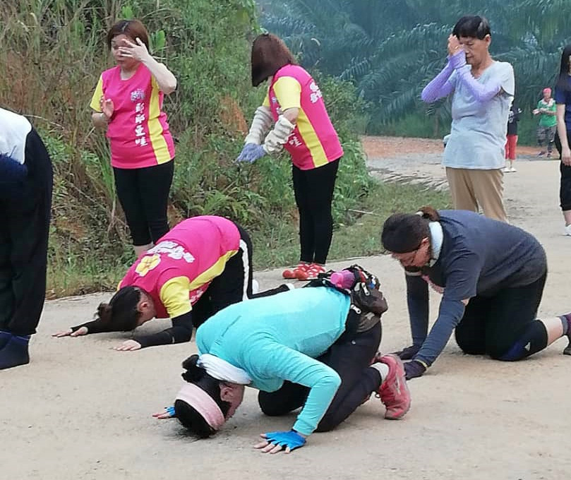 Seven people prostrating with three wearing matching bright pink and yellow shirts.