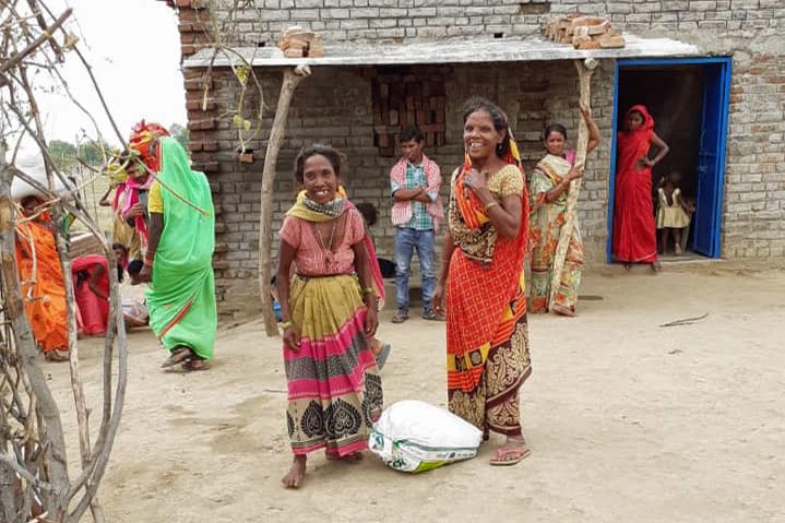 Two villagers with big smiles and a large bag on the ground between them.