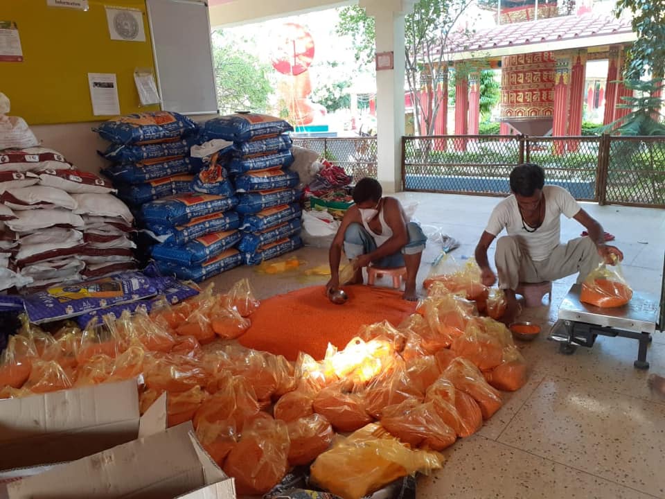 MD Shahid and Binod seated in front of a pile of loose and bagged food items in the process of making up packets for distribution.