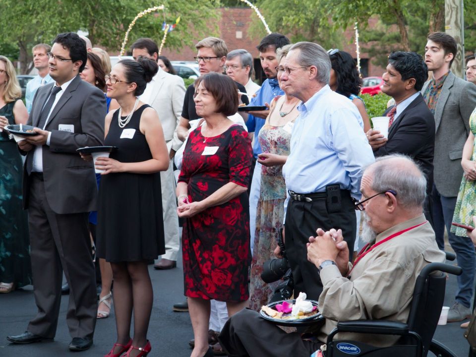 Party guests standing outside smiling and listening to a speaker off camera.