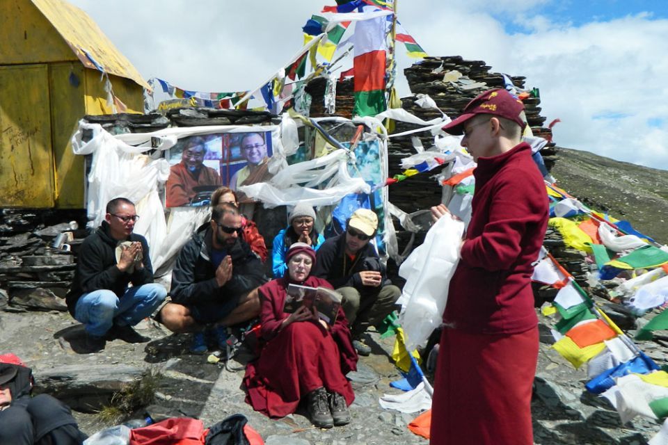 Group on the top of Drilbu Ri peak reciting prayers together with a pre-existing altar and prayer flags on the peak in the background.