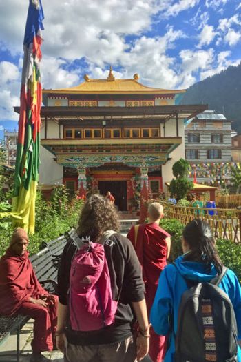 Tushita staff standing under a beautiful blue sky with white clouds looking at a colorful tibetan temple in front of them.