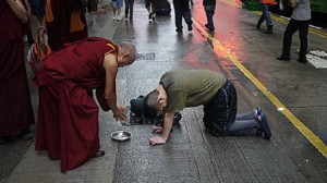 Lama Zopa Rinpoche making offerings to a street person in Hong Kong, 2010.