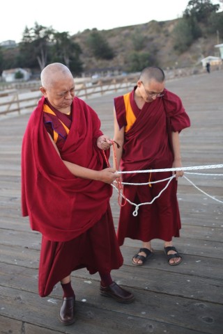 Lama Zopa Rinpoche holding ropes attached to mantra boards blessing beings in the ocean, Aptos, California, September 14, 2013. Photo by Ven. Thubten Kunsang.