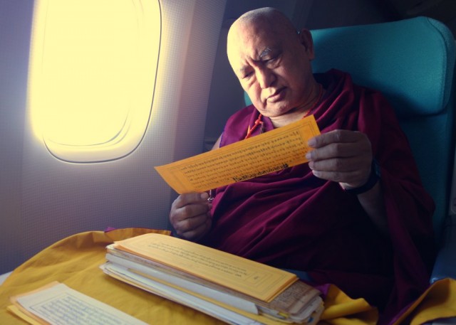 Rinpoche reads texts and meditates while flying, November 22, 2012. Photo Ven.Roger Kunsang.