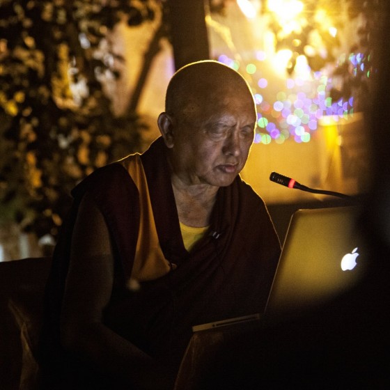 Lama Zopa Rinpoche reading Golden Light Sutra at Mahabodhi Temple, Bodhgaya, India, March 2014. Photo by Andy Melnic.