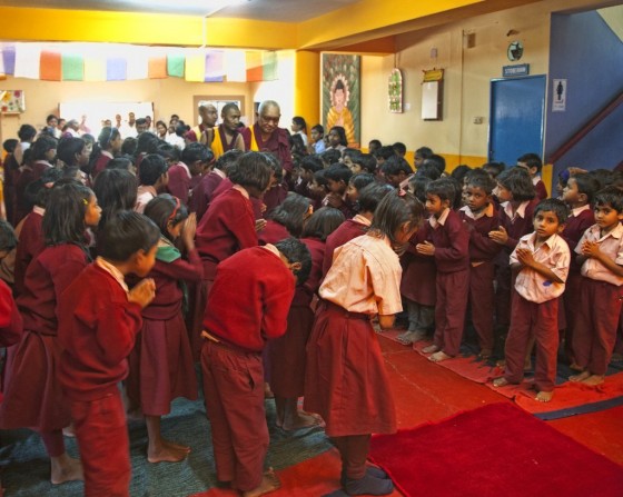 Lama Zopa Rinpoche being greeted by the children of Maitreya School and Tara Children's Home, Root Institute, Bodhgaya, India, March 2014. Photo by Andy Melnic.