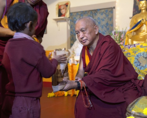 Lama Zopa Rinpoche offering gifts to children from Maitreya School and Tara Children's Project at Root Institute, Bodhgaya, India, March 2014. Photo by Andy Melnic.
