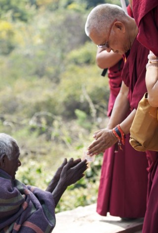Lama Zopa Rinpoche making an offering to a beggar on the way up to Vulture's Peak, India, March 2014. Photo by Andy Melnic.